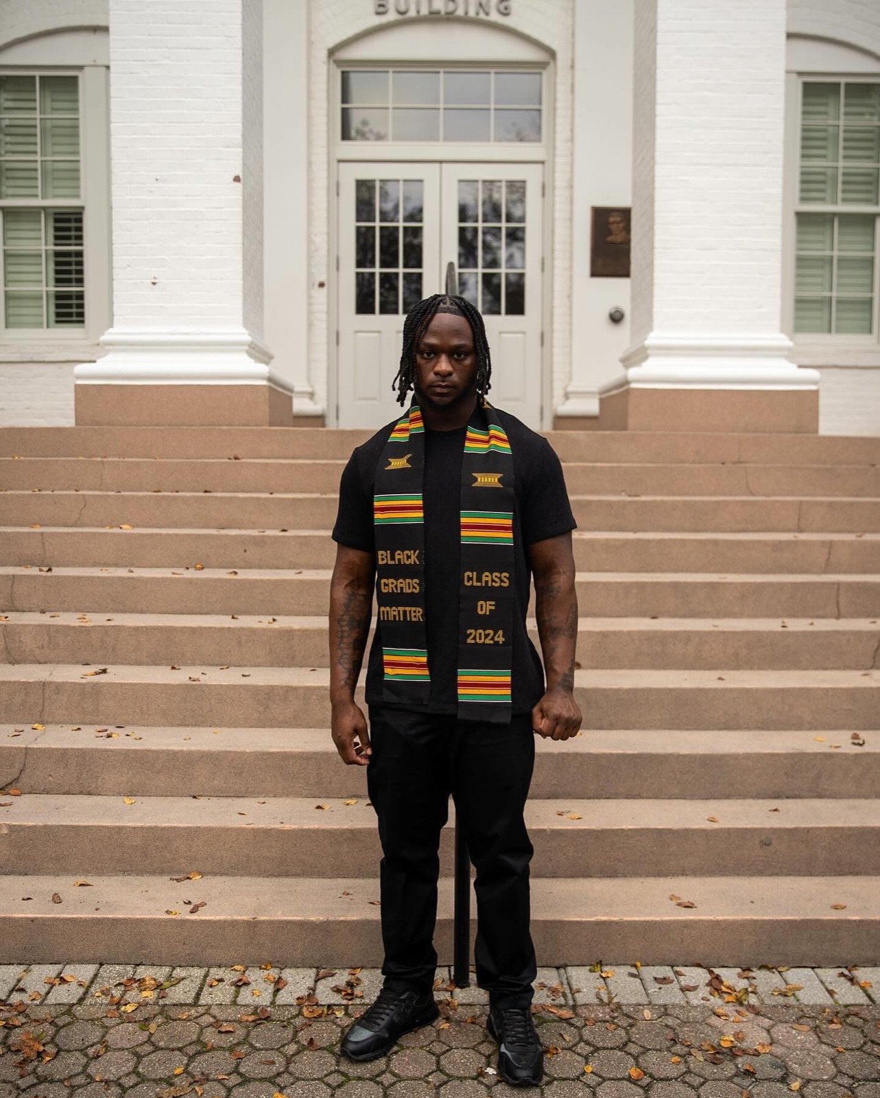 Marques Watson Trent at his Georgia Southern graduation, Class of 2024, standing on the steps in a kente graduation stole