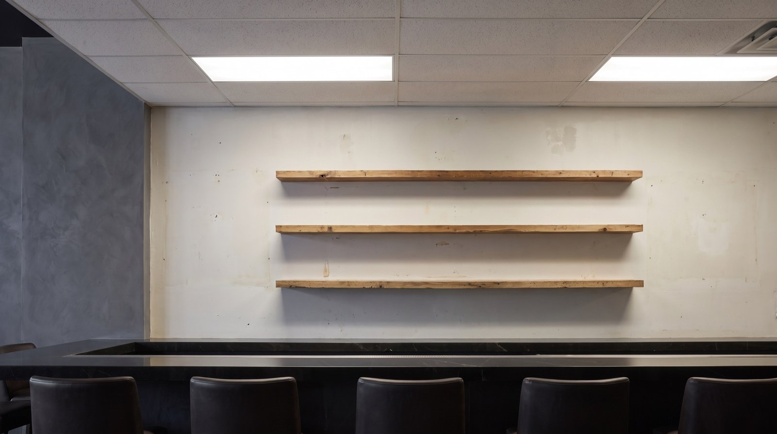 Bar before: plain painted drywall and basic wooden shelves behind the counter