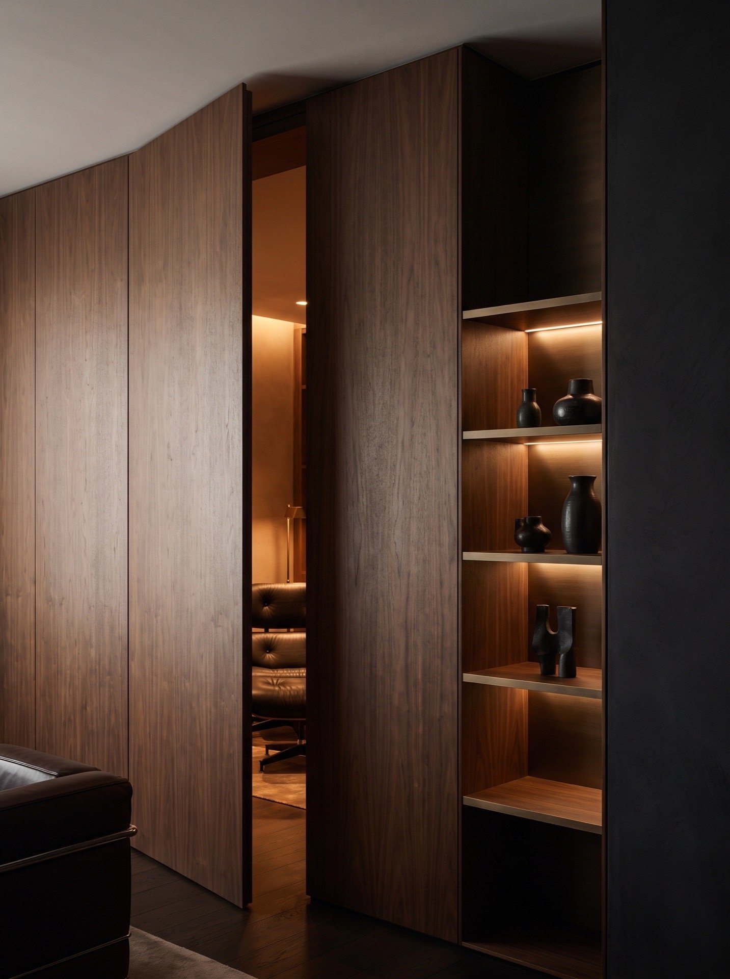 Hidden door standing open in a wall of flush walnut panels